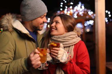 Happy couple with mulled wine at winter fair