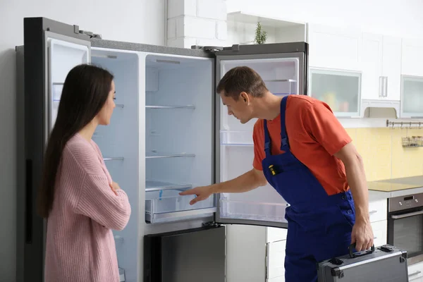 Manlig tekniker pratar med kunden nära kylskåp i köket — Stockfoto