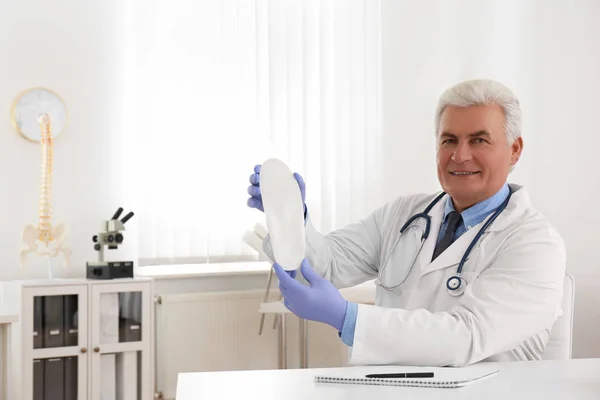 stock image Senior male orthopedist showing insole in clinic