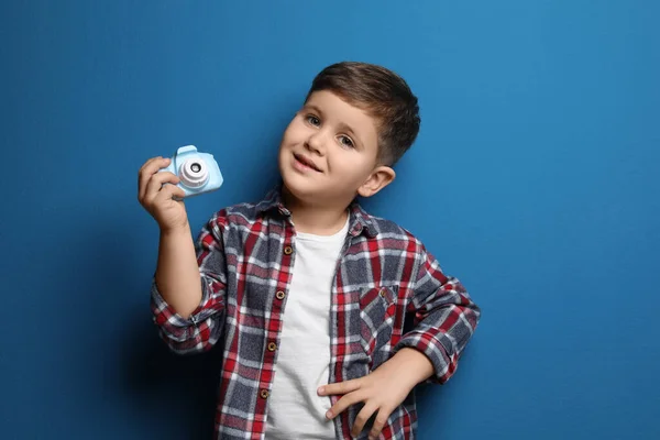 Kleine fotograaf met speelgoedcamera op blauwe achtergrond — Stockfoto