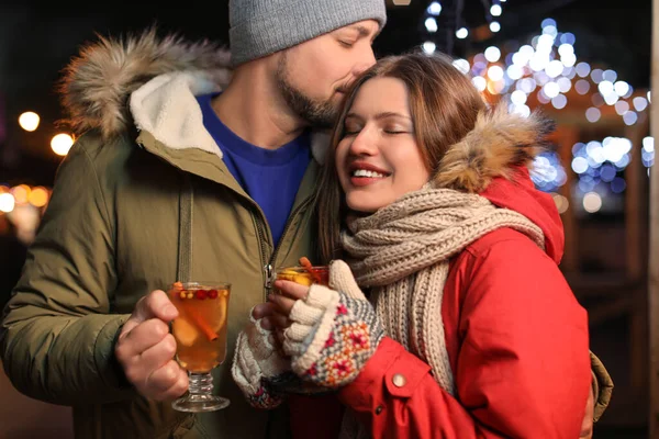 Happy couple with mulled wine at winter fair