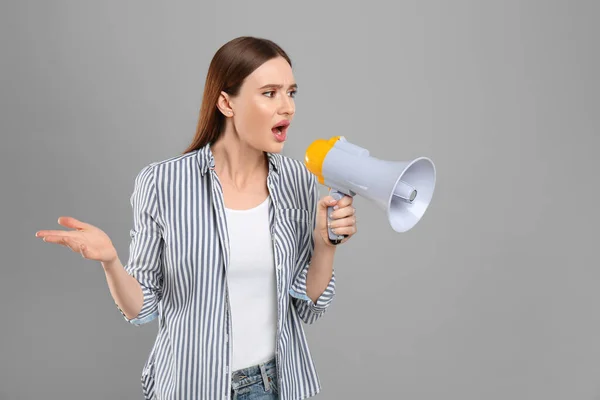 Känslomässig ung kvinna med megafon på ljusgrå bakgrund — Stockfoto