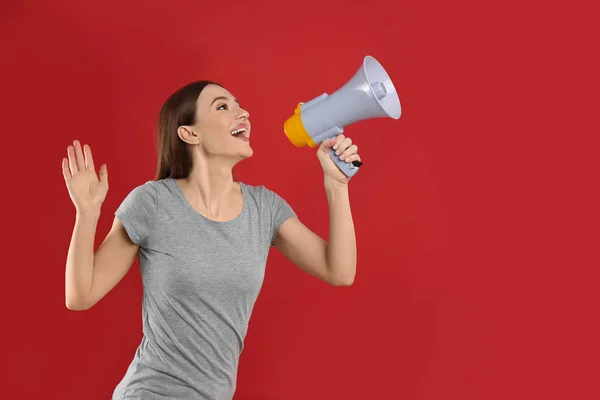 Jovem com megafone no fundo vermelho. Espaço para texto — Fotografia de Stock