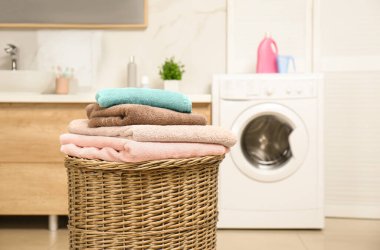 Wicker basket with laundry and washing machine in bathroom