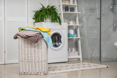 Wicker basket with laundry and washing machine in bathroom