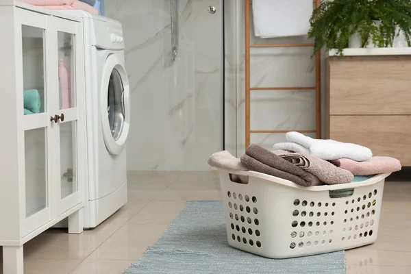 Корзина с прачечной и стиральной машиной в ванной комнате — стоковое фото