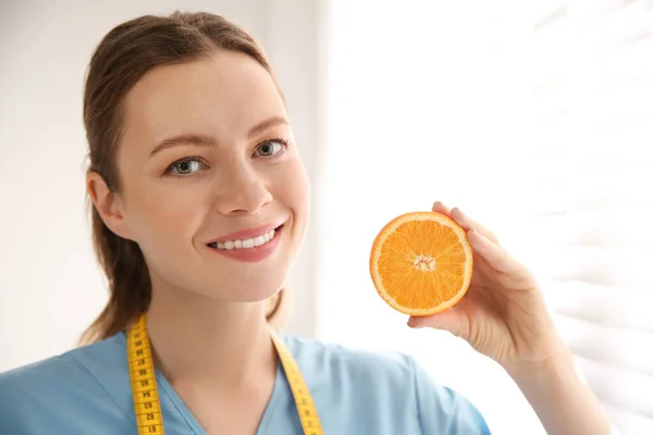 Voedingsdeskundige met oranje bij venster op kantoor — Stockfoto