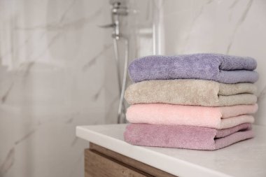 Banyodaki beyaz masanın üzerinde bir yığın temiz havlu. Metin için boşluk