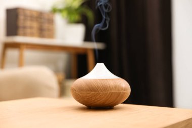 Aroma yağı yayıcı evdeki ahşap masada. Oda spreyi