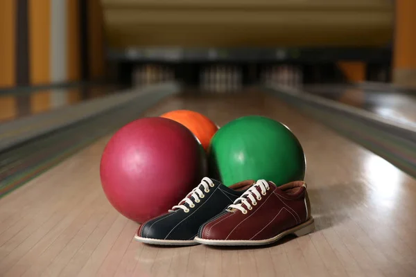 Shoes and balls on bowling lane in club