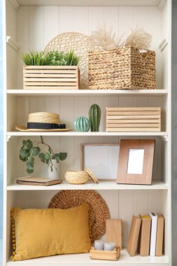 Bitkilerle dolu beyaz raf ünitesi ve farklı dekoratif malzemeler.