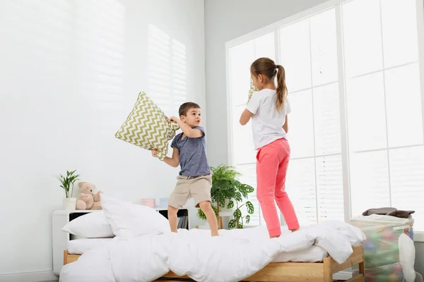 Niños felices teniendo pelea de almohadas en el dormitorio —  Fotos de Stock