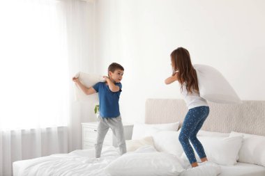 Mutlu çocuklar yatak odasında yastık savaşı yapıyor.