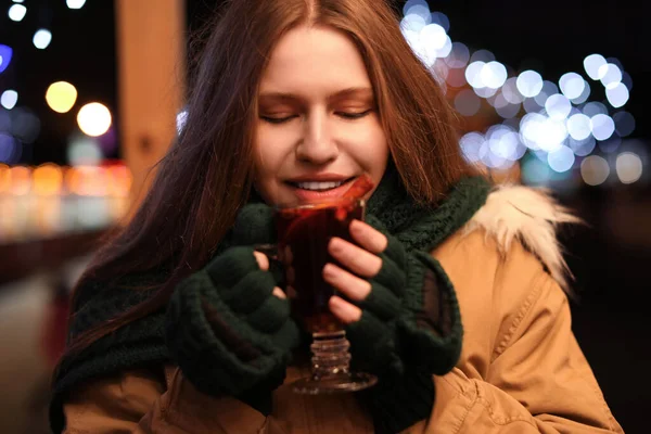 Щаслива жінка зі смачним глінтвейном на зимовому ярмарку — стокове фото