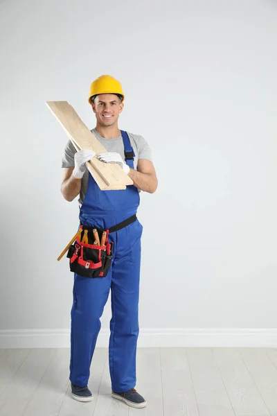 Hermoso carpintero con tablones de madera cerca de la pared de luz —  Fotos de Stock