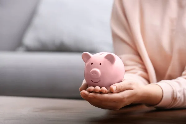 Woman with piggy bank at wooden table, closeup. Space for text — Stock Photo, Image