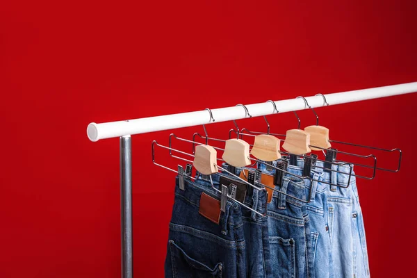 Cremalheira com jeans diferentes no fundo vermelho — Fotografia de Stock