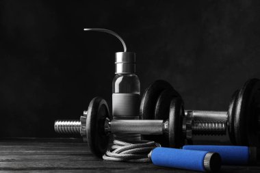 Ahşap zeminde koyu renk arka planda spor aletleri ve aksesuarlar.