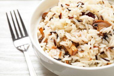 Delicious rice pilaf with mushrooms on white table, closeup