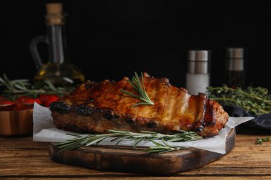 Tasty grilled ribs with rosemary on wooden table clipart