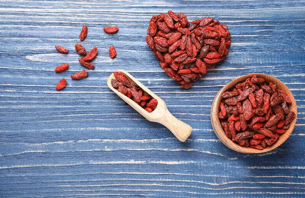 Flat lay composition with dry goji berries on blue wooden table — Stock Photo, Image