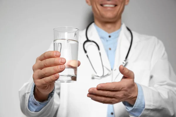 Voedingsdeskundige met glas zuiver water op lichtgrijze achtergrond — Stockfoto