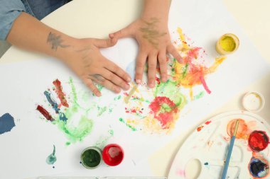 Masada avuç içi resim yapan küçük bir çocuk.