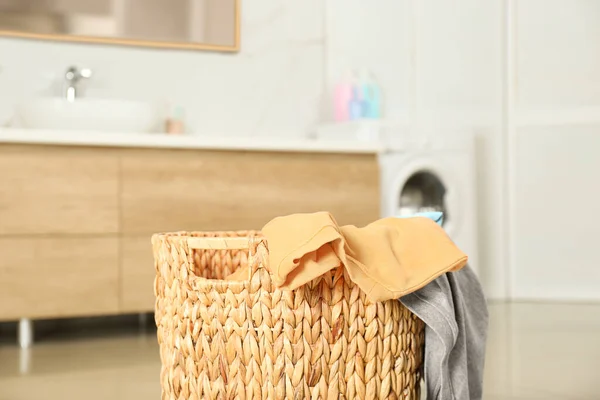 Wicker basket with dirty laundry in bathroom
