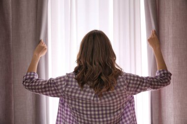 Evde perdeleri açan kadın, arka manzara