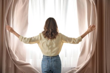 Evde perdeleri açan kadın, arka manzara
