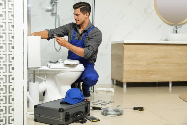 Fontanero profesional trabajando con inodoro en el baño —  Fotos de Stock