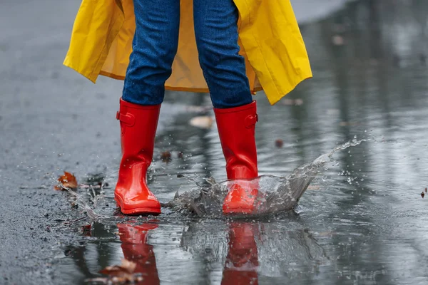 Femme éclaboussant dans la flaque d'eau à l'extérieur le jour de pluie, gros plan — Photo