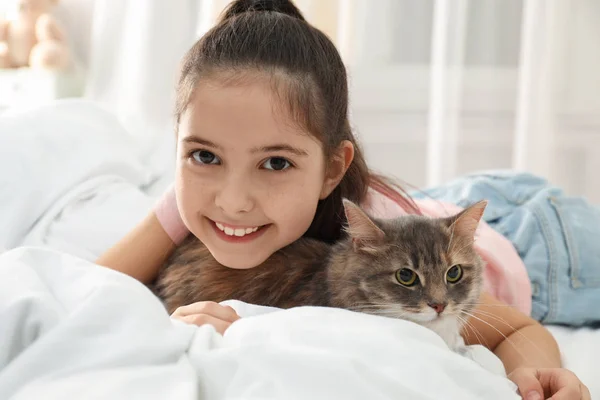 Nettes kleines Mädchen mit Katze, die zu Hause auf dem Bett liegt. erstes Haustier — Stockfoto