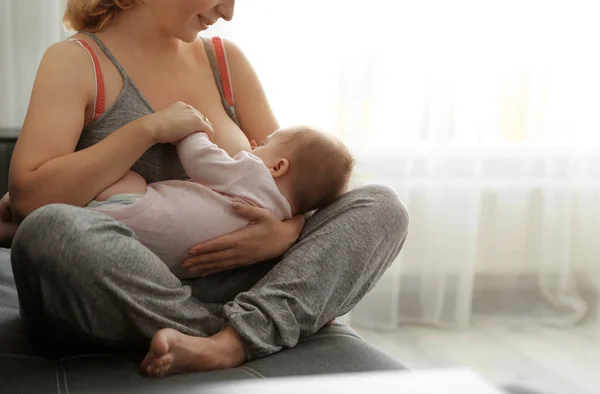 Jovem mulher amamentando seu bebê em casa — Fotografia de Stock