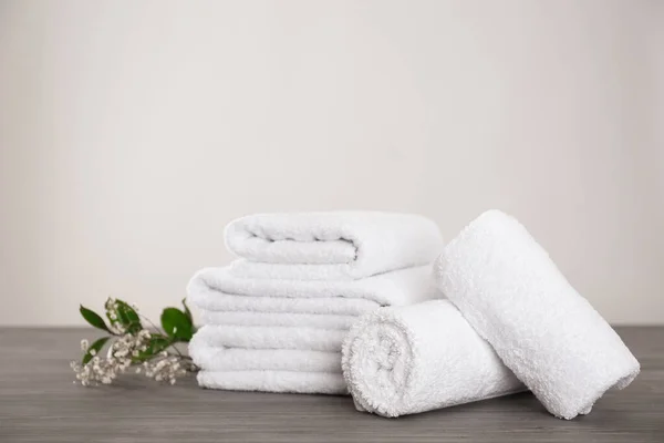 Färska vita handdukar och grön planta på grått träbord — Stockfoto