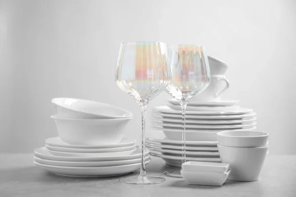 Set de platos y vasos limpios sobre mesa gris claro —  Fotos de Stock