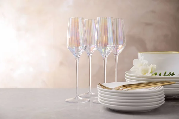 Set glazen en borden met bloemen op lichtgrijze tafel — Stockfoto