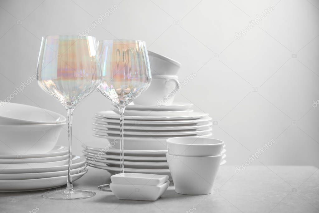 Set of clean dishes and glasses on light grey table