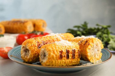 Açık gri masada leziz ızgara mısır koçanları.