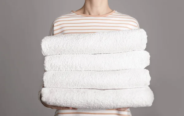 Woman holding fresh towels on grey background, closeup — Stock Photo, Image