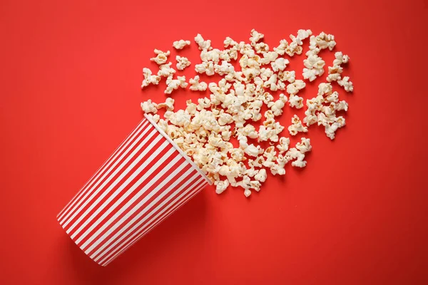 Umgekippter Pappbecher Mit Leckerem Popcorn Auf Rotem Hintergrund Draufsicht — Stockfoto