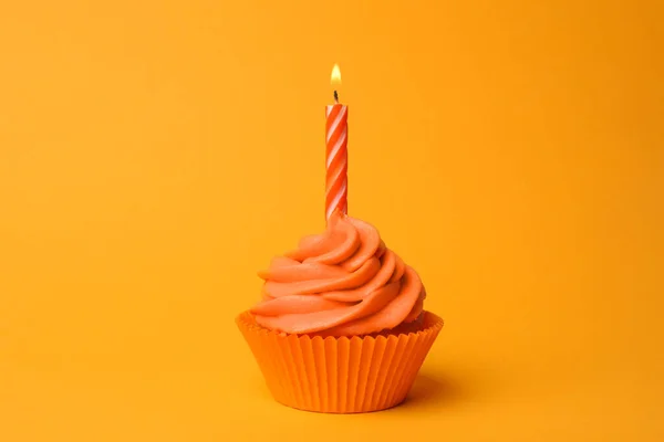 Lahodný narozeninový dortík s pomerančovou smetanou a hořící svíčkou — Stock fotografie