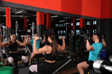 Spor salonunda dambıllarla çalışan çift.