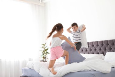 Mutlu çocuklar yatak odasında yastık savaşı yapıyor.