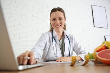 Nutritionist working with laptop at desk in office