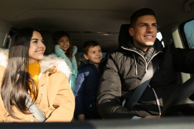 Happy family with little children inside modern car