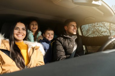 Happy family with little children inside modern car