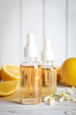 Beyaz ahşap masa üzerinde turunç, çiçek ve limon şişeleri.