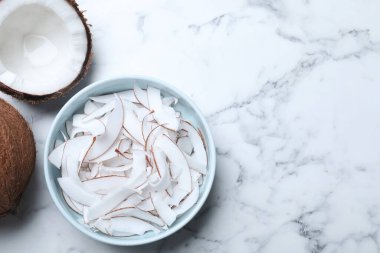 Flat lay composition with fresh coconut flakes on white marble table. Space for text