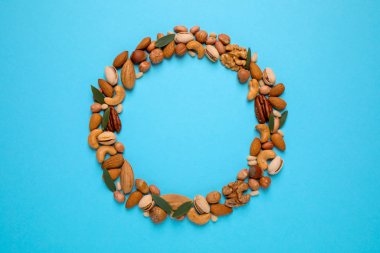 Açık mavi arka planda farklı lezzetli fındıklar, düz yatış. Metin için boşluk